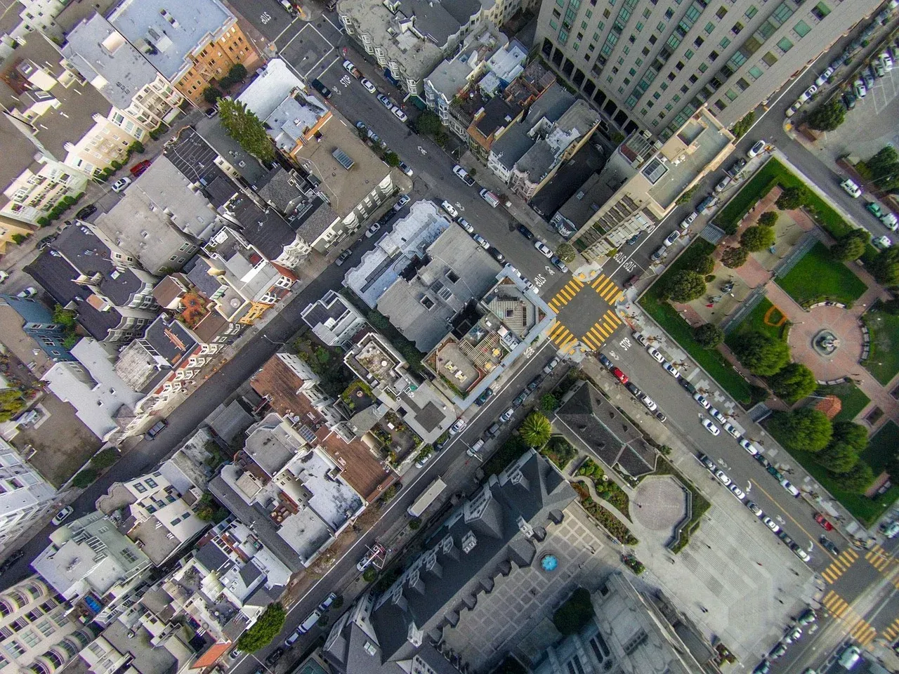 Vista aérea cenital de un cruce de calles con edificios y una plaza ajardinada