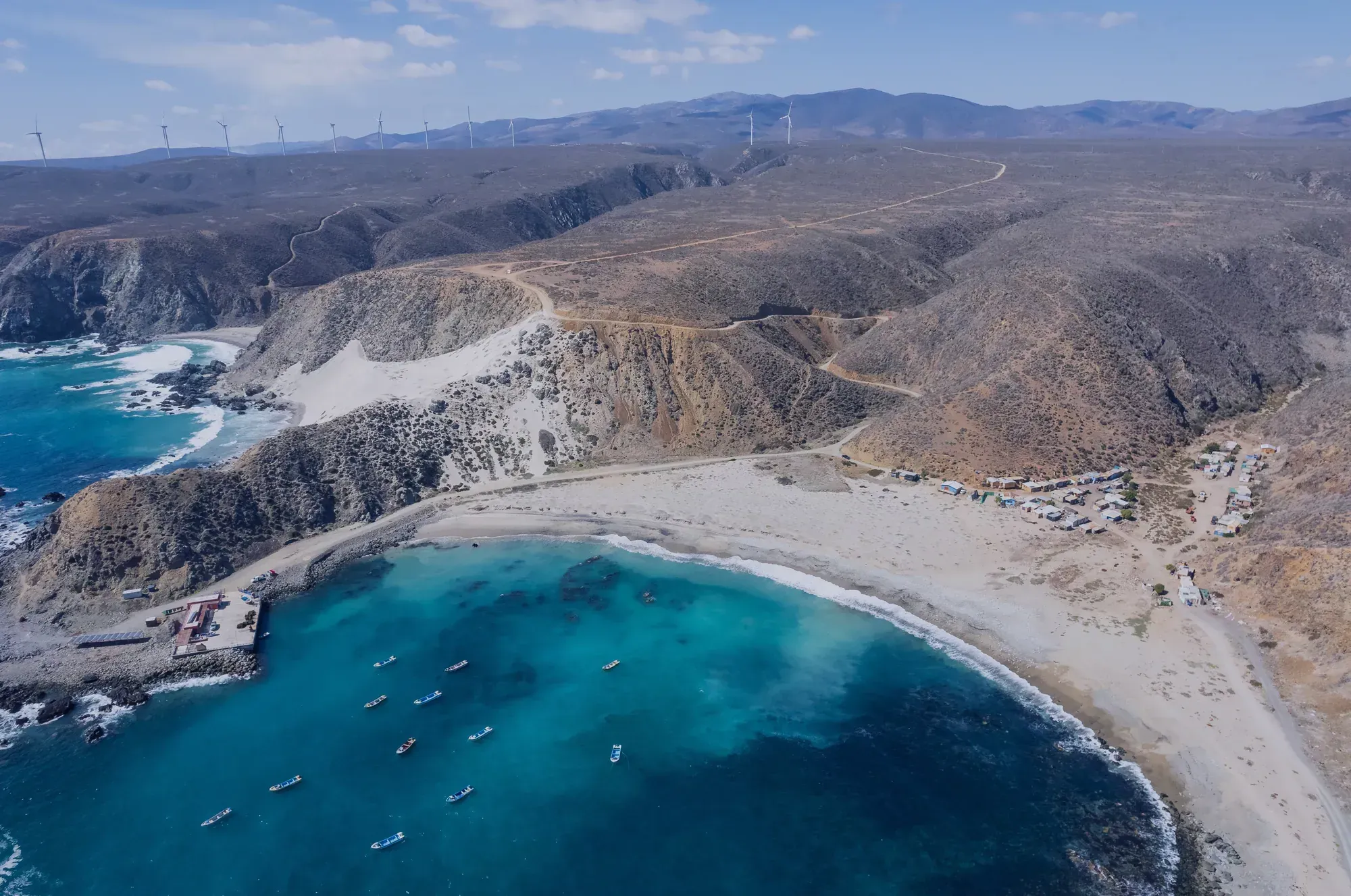 Bahía con barcas de pesca y aerogeneradores en las colinas, vista desde el aire