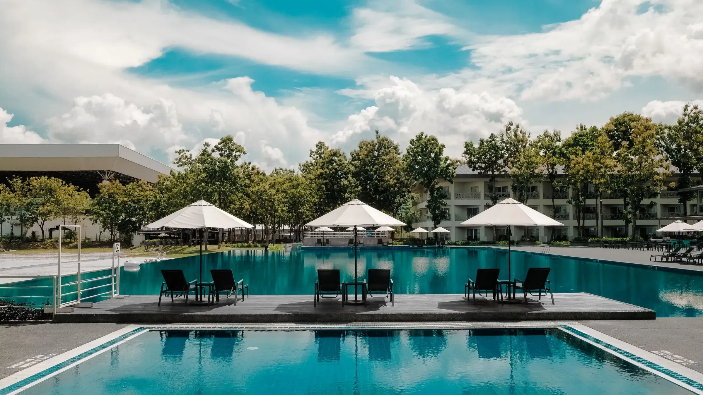 Piscina de un hotel con sombrillas y jardín